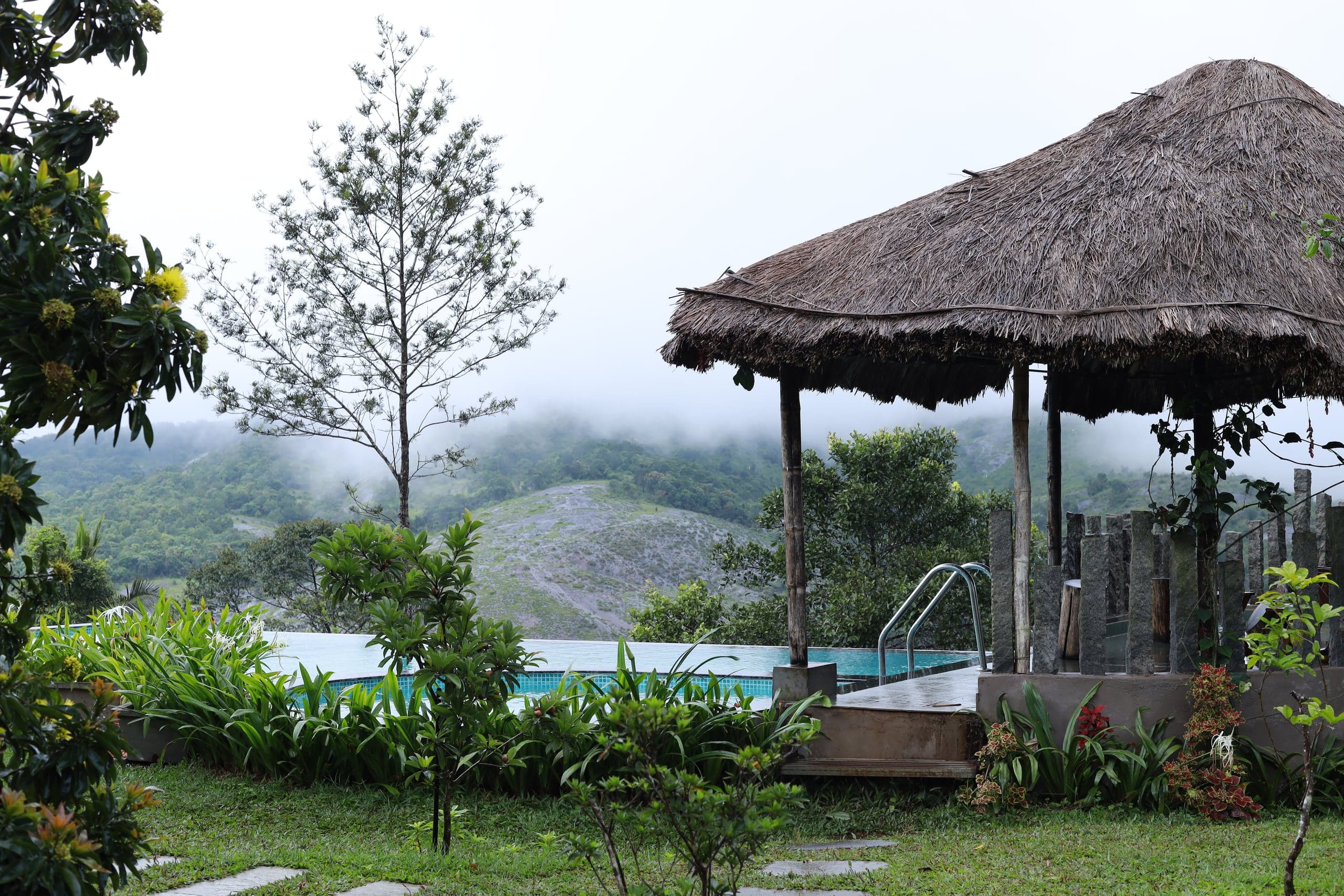 Infinity pool and thatched gazebo overlooking the misty valley at Heyday Vagamon hill resort, Idukki, Kerala