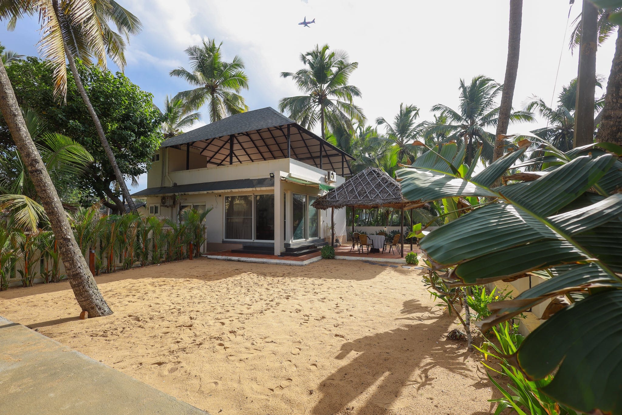 Whitewashed beach cottage with a thatched roof among coconut palms at Heyday by the Sea, Veli, Thiruvananthapuram, Kerala