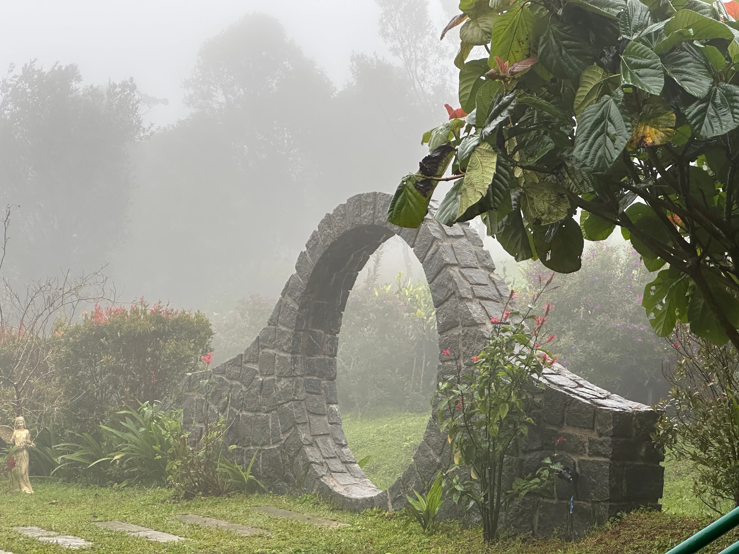 The stone moon gate in the misty garden at Heyday Vagamon, Vagamon, Idukki, Kerala